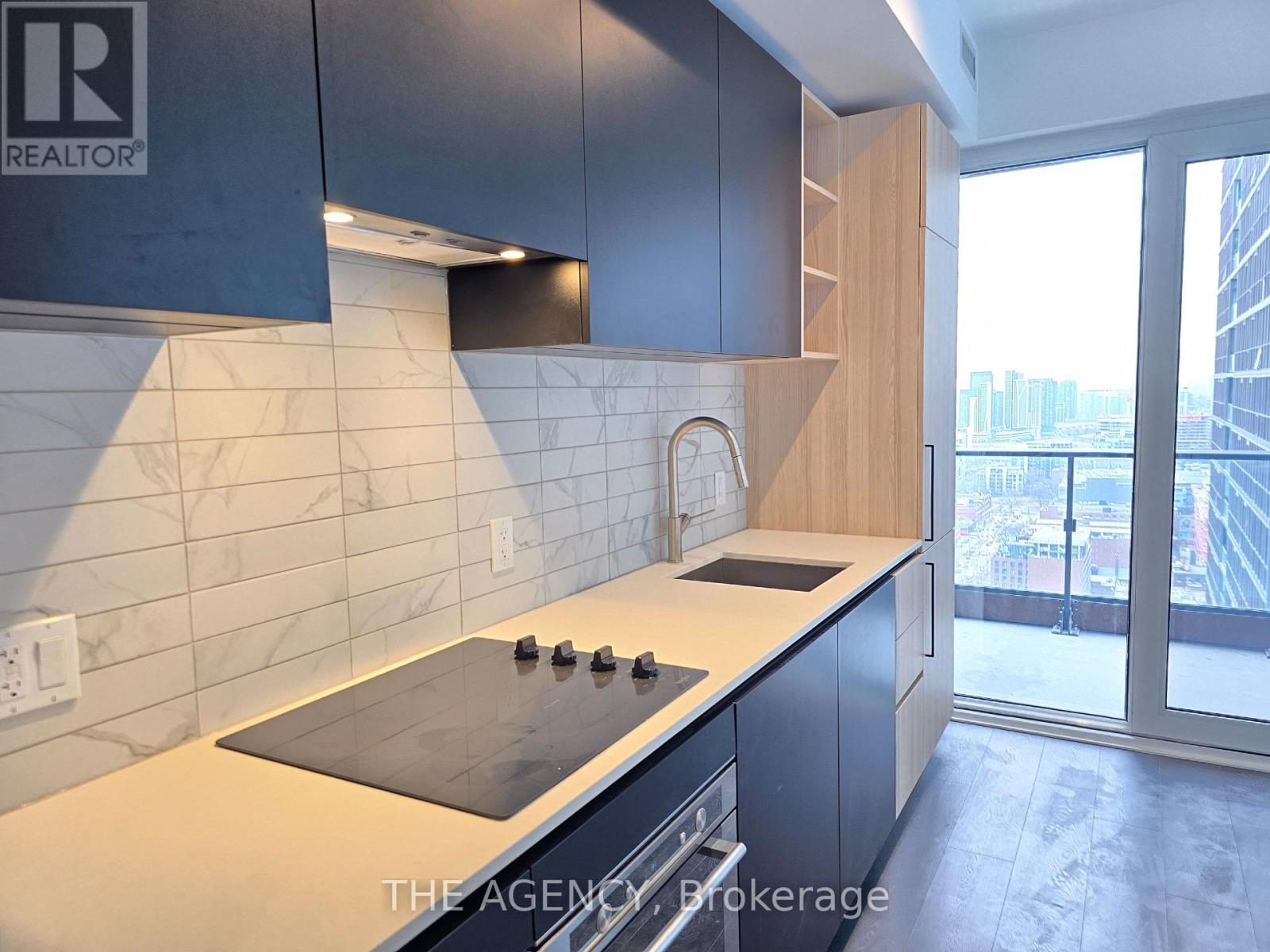 A kitchen with a stove top oven and a marble backsplash.