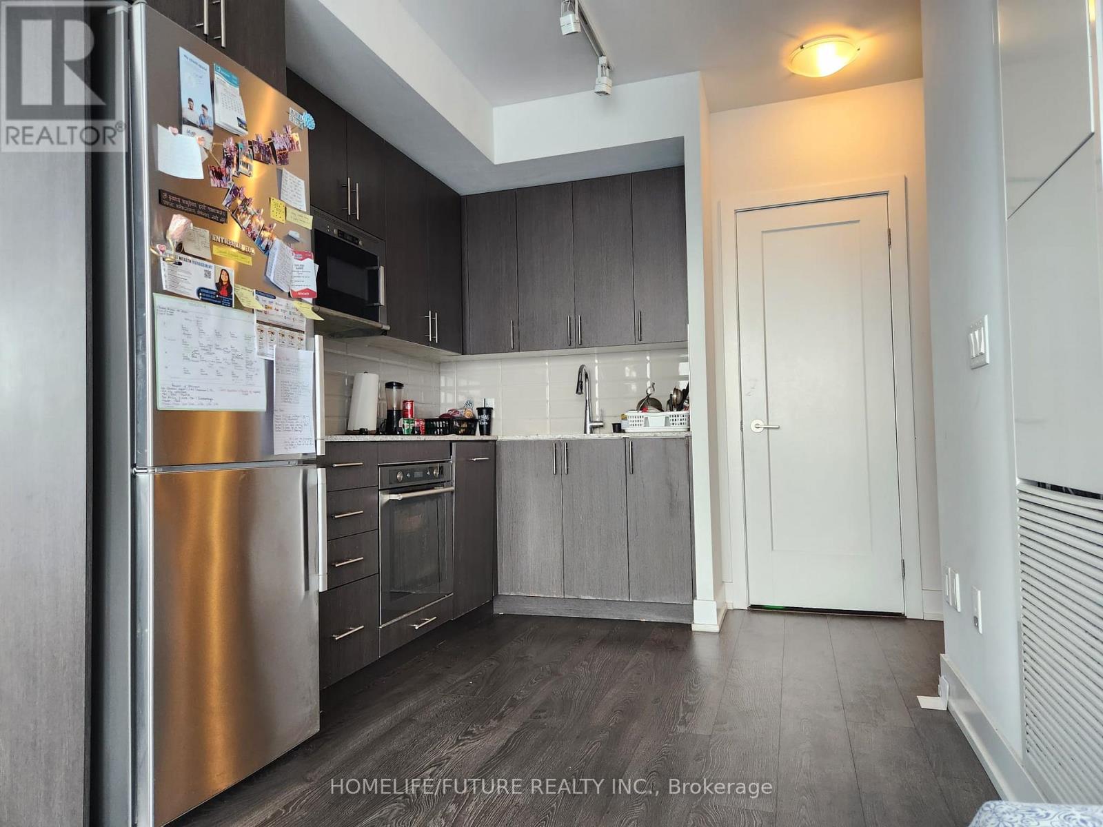 A kitchen with a refrigerator covered in papers.