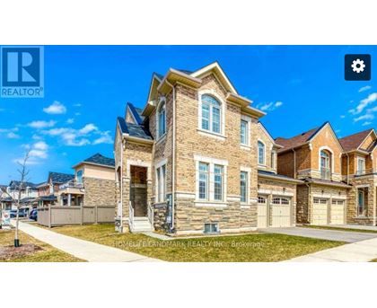 A large, well-maintained house with a stone facade and multiple garages is for sale.