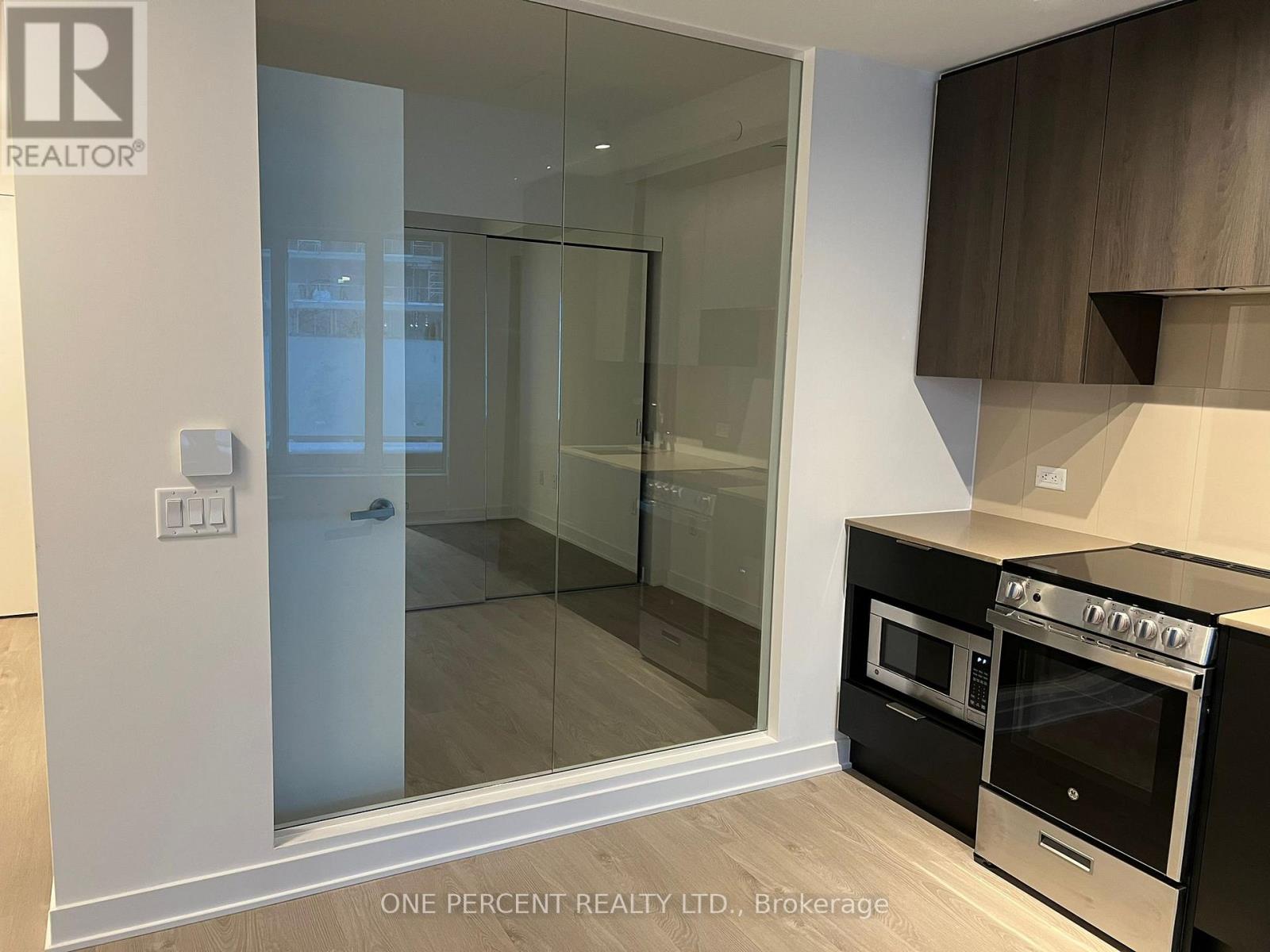 A modern kitchen with a glass door shower and a stove top oven.