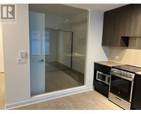 A modern kitchen with a glass door shower and a stove top oven.