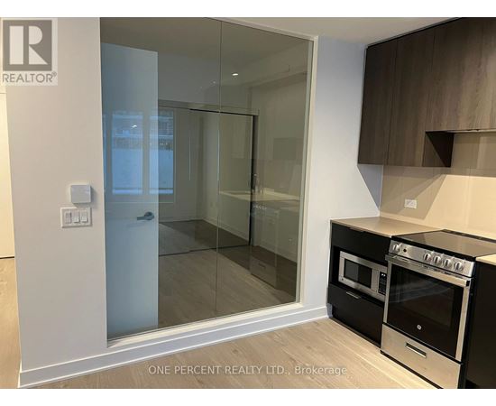 A modern kitchen with a glass door shower and a stove top oven.