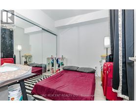 A bedroom with a red bedspread and a mirror on the wall.
