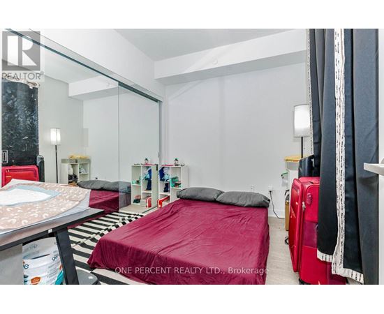 A bedroom with a red bedspread and a mirror on the wall.