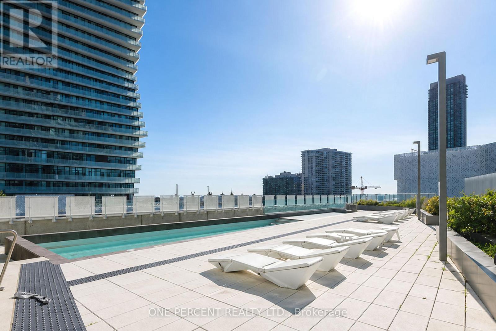 A sunny day at a rooftop pool with loungers and a view of the city.