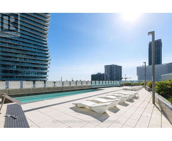 A sunny day at a rooftop pool with loungers and a view of the city.