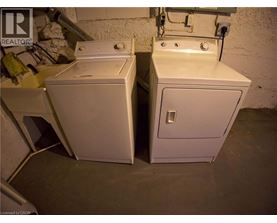 Two white washing machines in a basement.