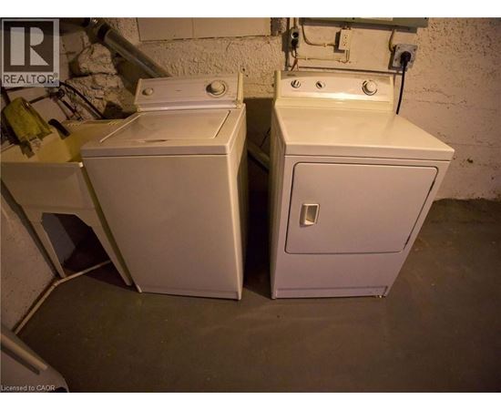Two white washing machines in a basement.