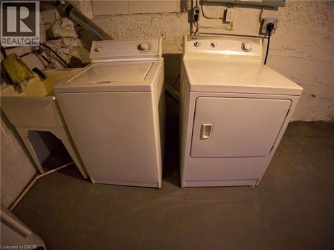 Two white washing machines in a basement.