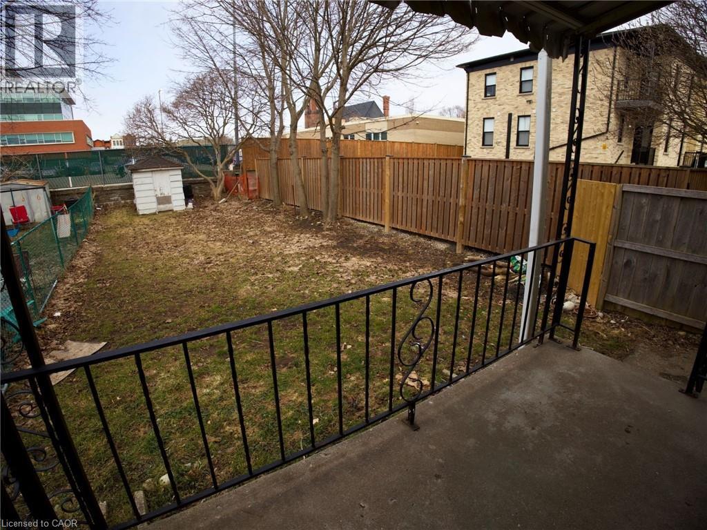A backyard with a black fence and a green tree.