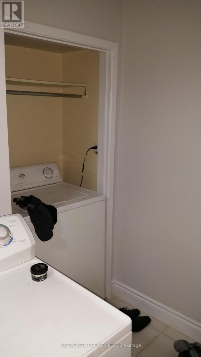 A bathroom with a toilet, towel rack, and a pair of black shoes.