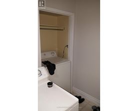 A bathroom with a toilet, towel rack, and a pair of black shoes.
