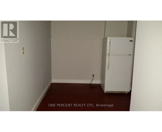 A white refrigerator in a room with white walls.