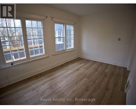 A room with wooden floors and white walls, with windows on the left side.