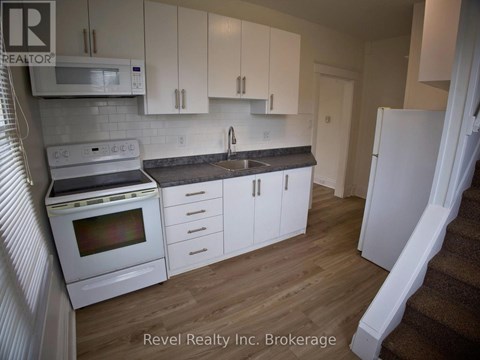 A kitchen with white cabinets and appliances is for sale.