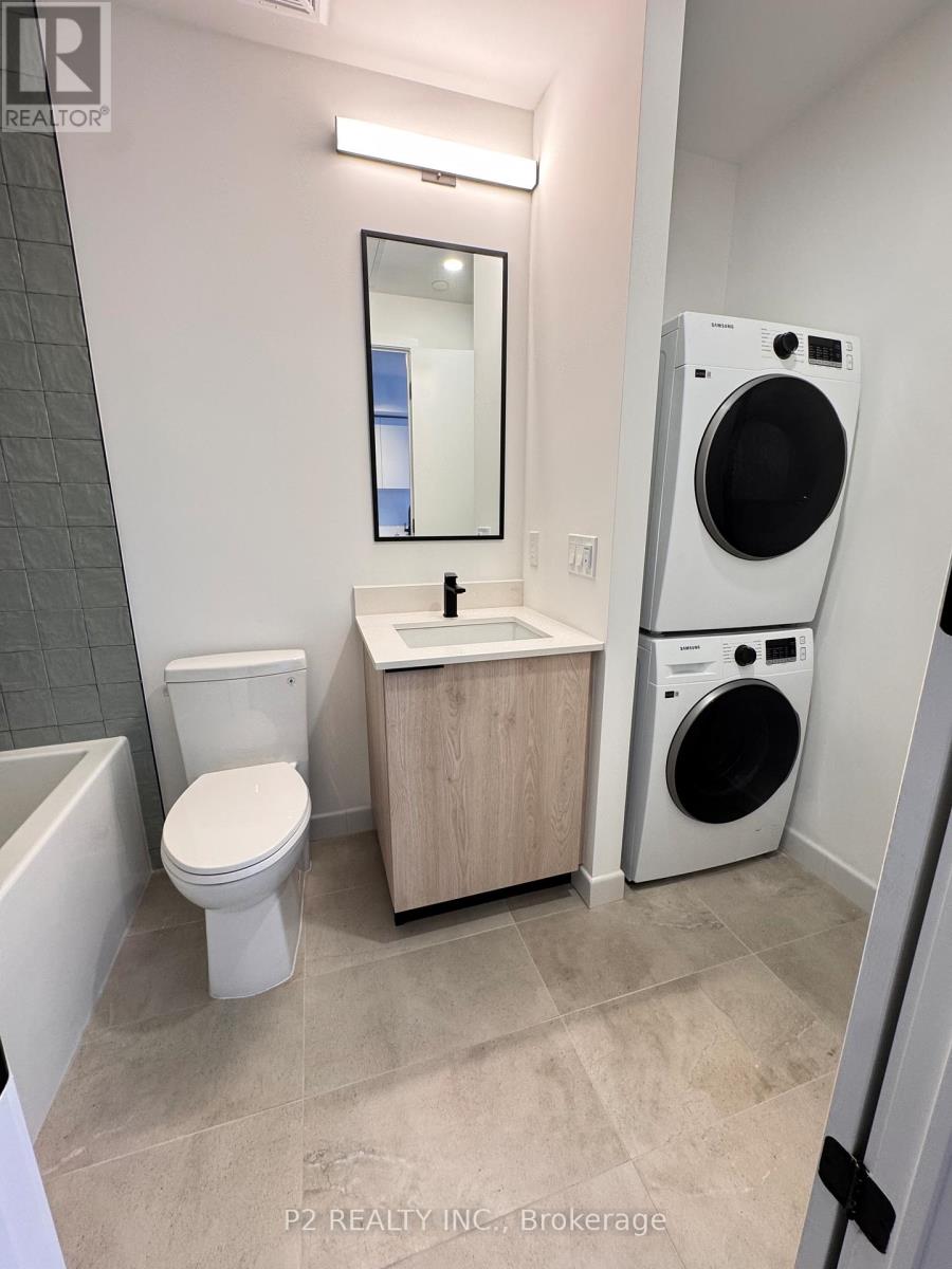 A small bathroom with a toilet, sink, and a washer and dryer.