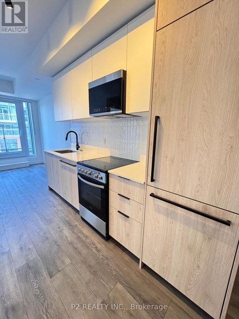 A kitchen with wooden cabinets and a black microwave above the stove.