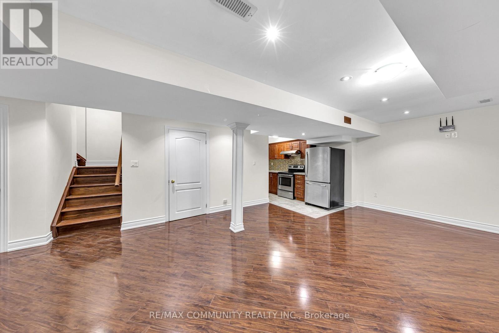 A spacious room with wood flooring and white walls.