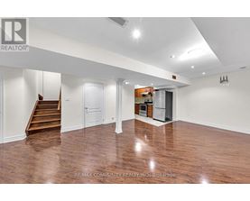 A spacious room with wood flooring and white walls.