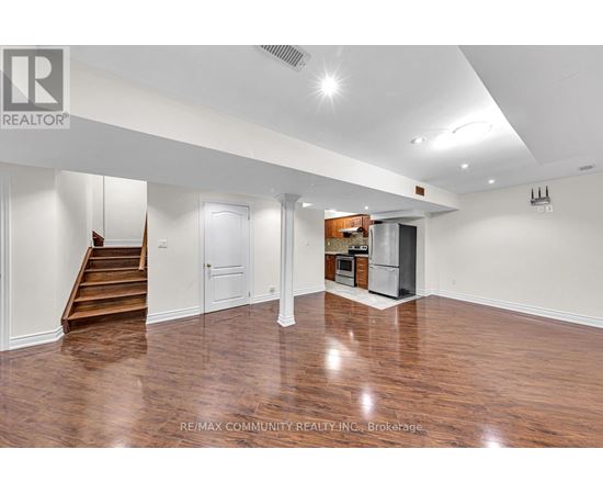 A spacious room with wood flooring and white walls.