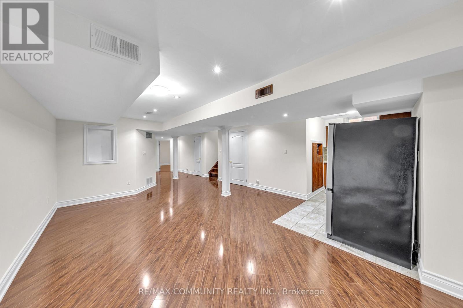 A spacious room with wooden flooring and white walls.