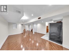 A spacious room with wooden flooring and white walls.