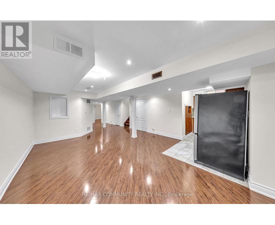 A spacious room with wooden flooring and white walls.