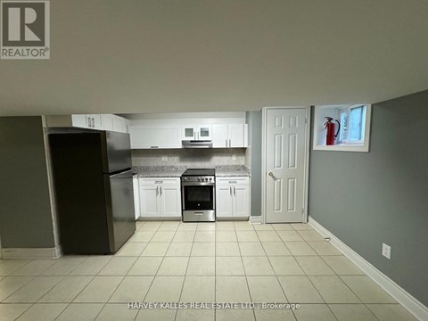A kitchen with white cabinets and a black fridge is shown.