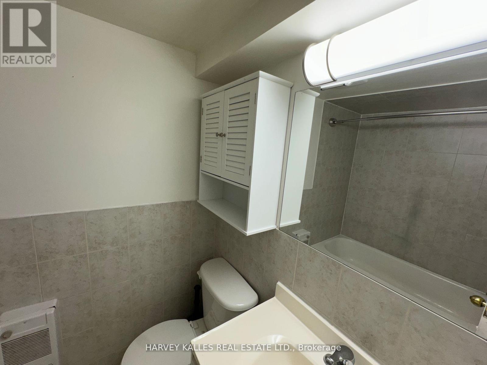 A bathroom with a toilet, a cabinet, and a shower.