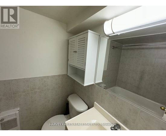 A bathroom with a toilet, a cabinet, and a shower.