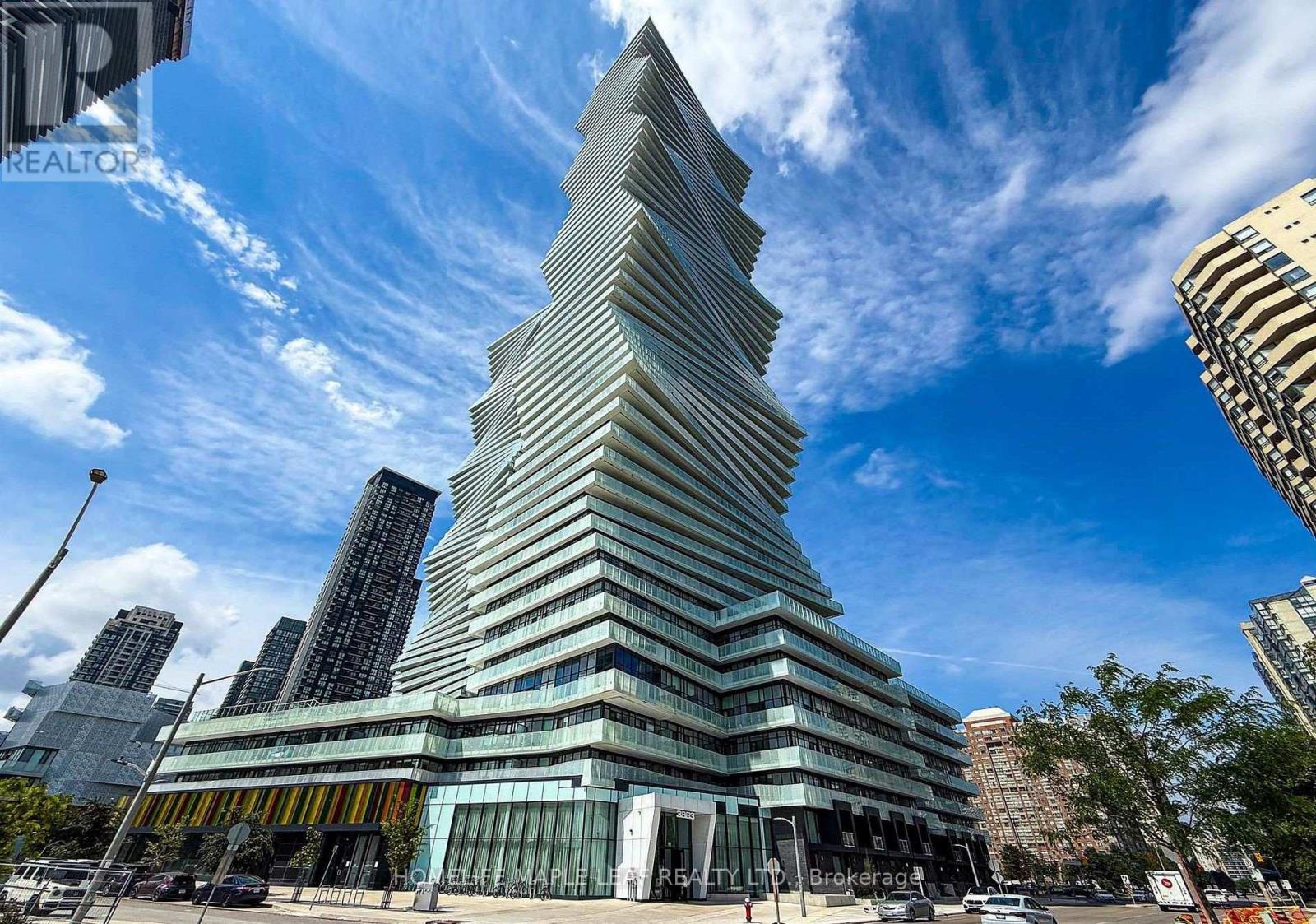 A tall, modern building with a unique triangular shape stands out in a cityscape.