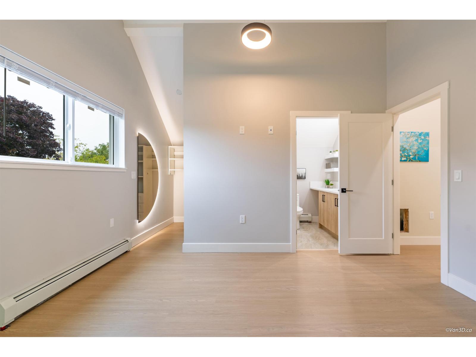 A spacious, empty room with a large window on the left side and a door on the right side.