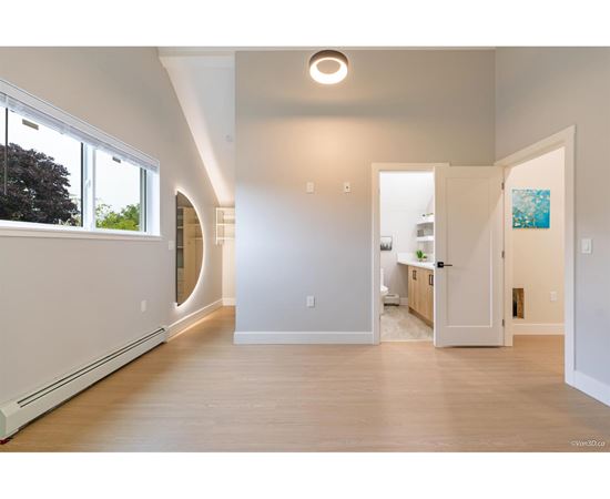 A spacious, empty room with a large window on the left side and a door on the right side.