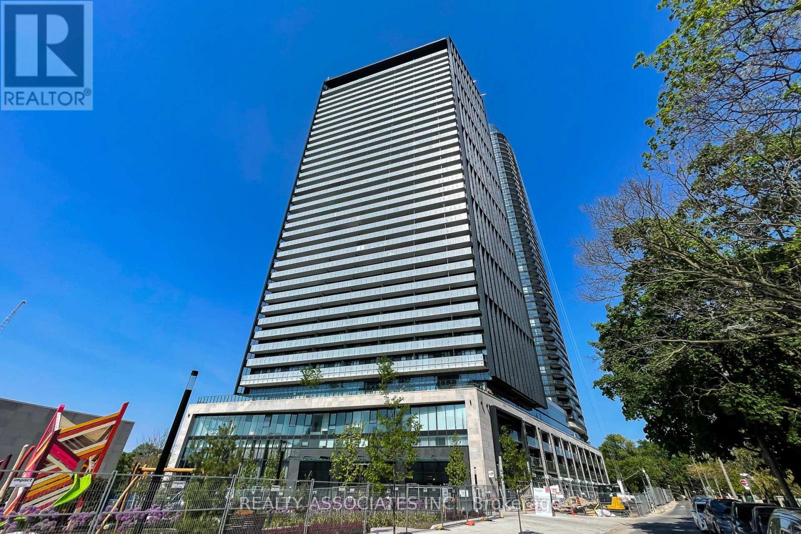 A tall building with a glass facade stands in front of a clear blue sky.