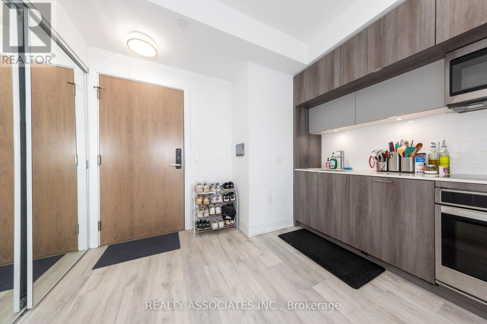 A kitchen with wooden cabinets and a black mat on the floor.