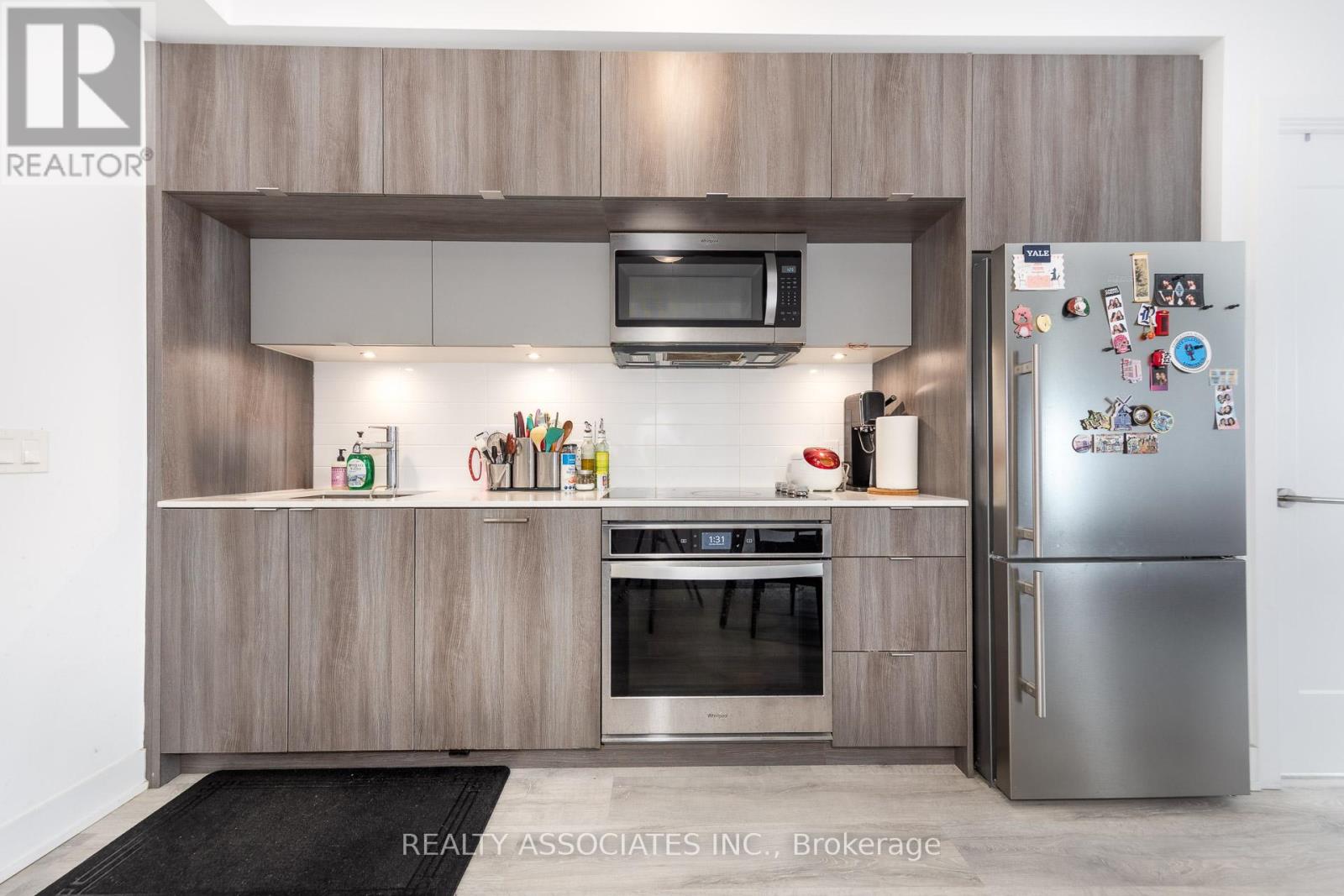 A modern kitchen with a refrigerator covered in magnets.
