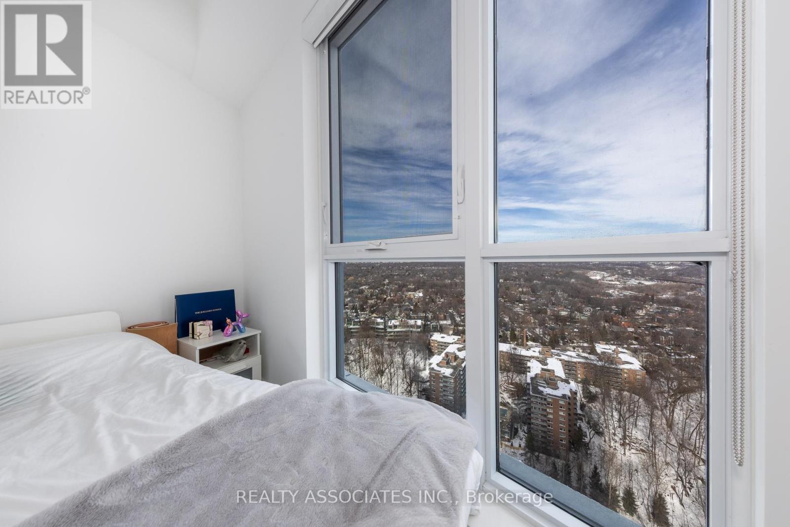 A bedroom with a large window overlooking a snowy cityscape.