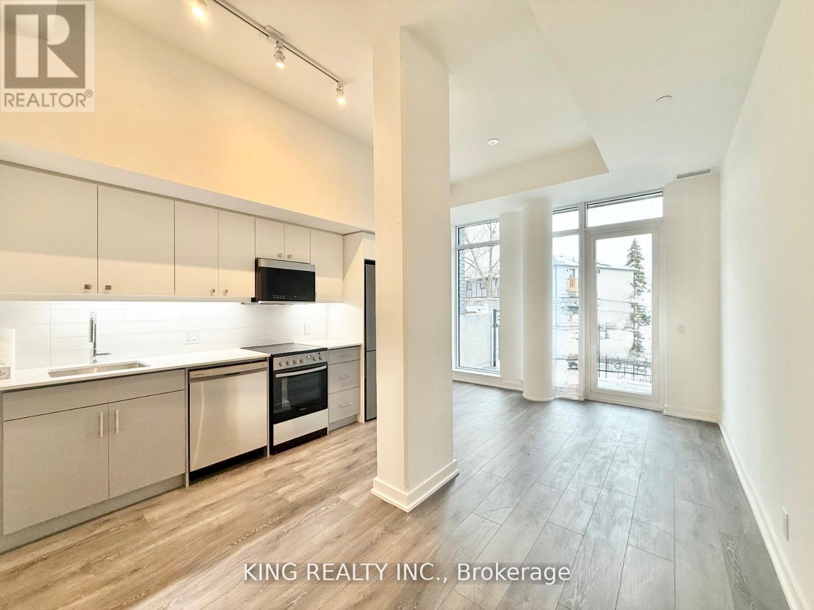 A modern kitchen with white cabinets and a wooden floor.