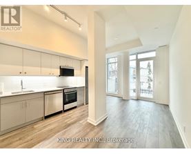 A modern kitchen with white cabinets and a wooden floor.