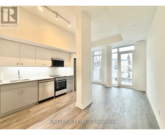 A modern kitchen with white cabinets and a wooden floor.