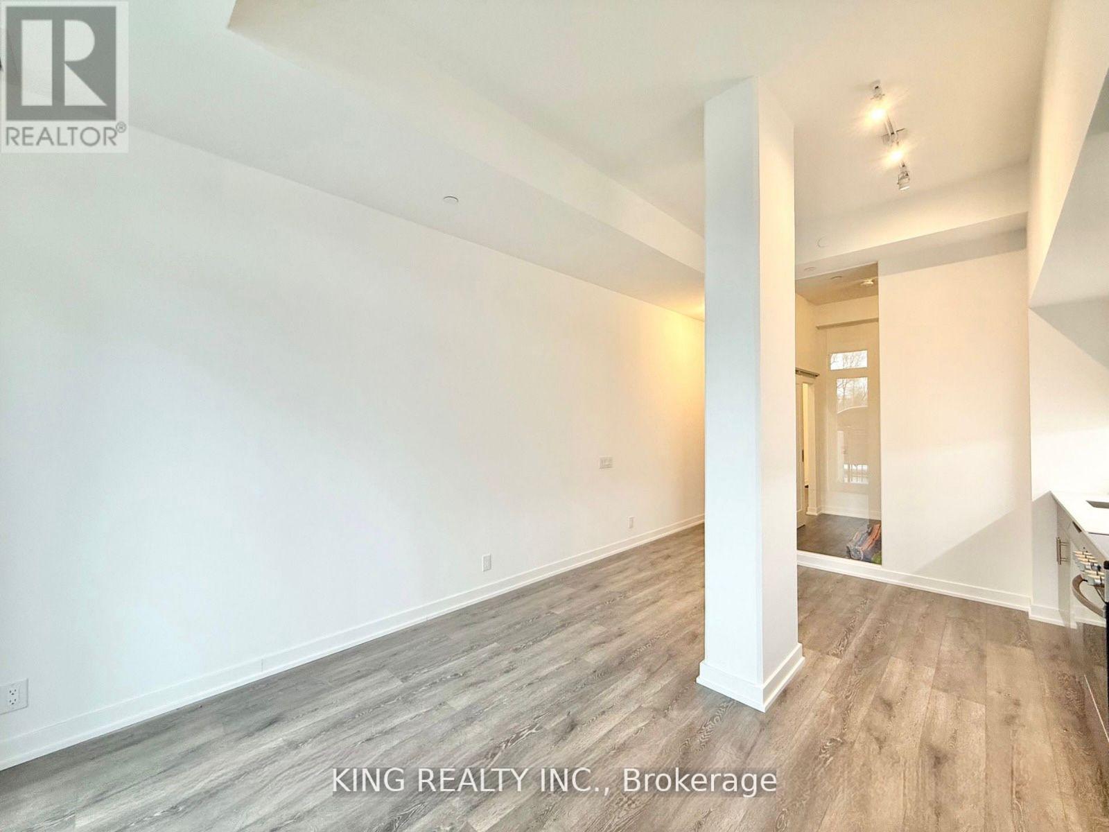 A spacious room with wooden flooring and white walls, part of a property listing by King Realty Inc. in Brokerage.