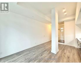 A spacious room with wooden flooring and white walls, part of a property listing by King Realty Inc. in Brokerage.
