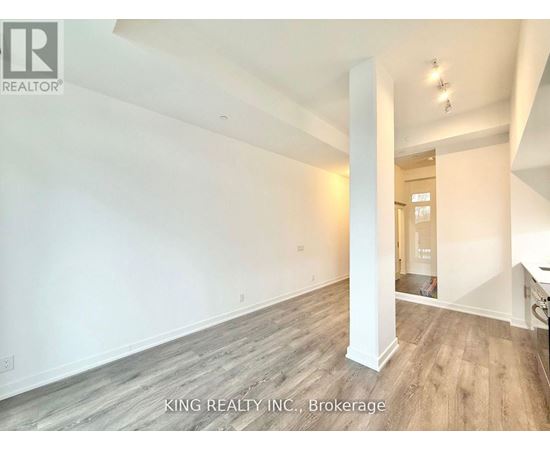 A spacious room with wooden flooring and white walls, part of a property listing by King Realty Inc. in Brokerage.