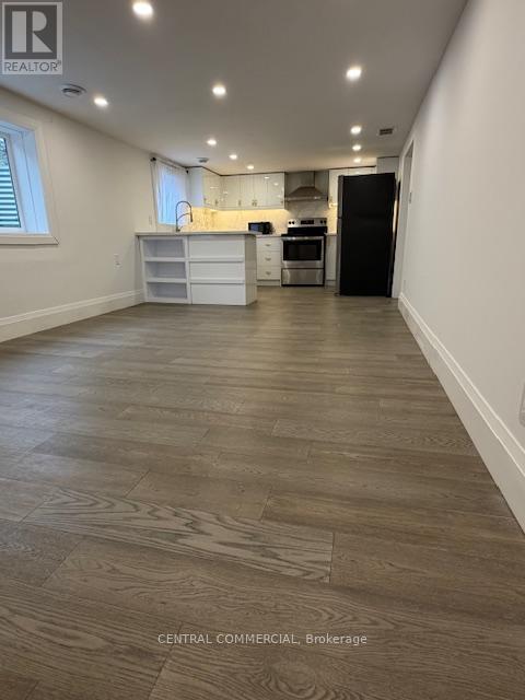 A spacious kitchen with a black refrigerator and white cabinets.