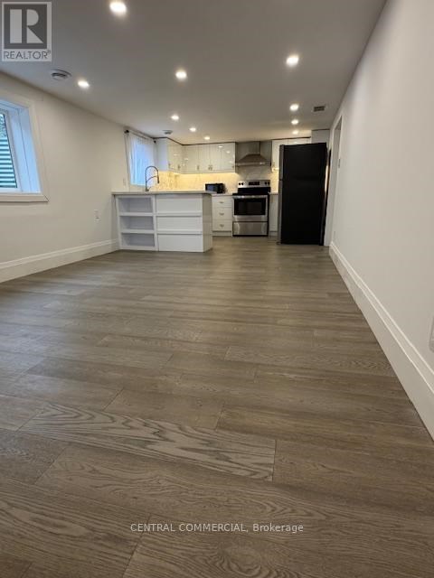 A spacious kitchen with a black refrigerator and white cabinets.