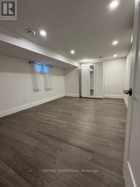 A spacious room with wooden flooring and white walls.