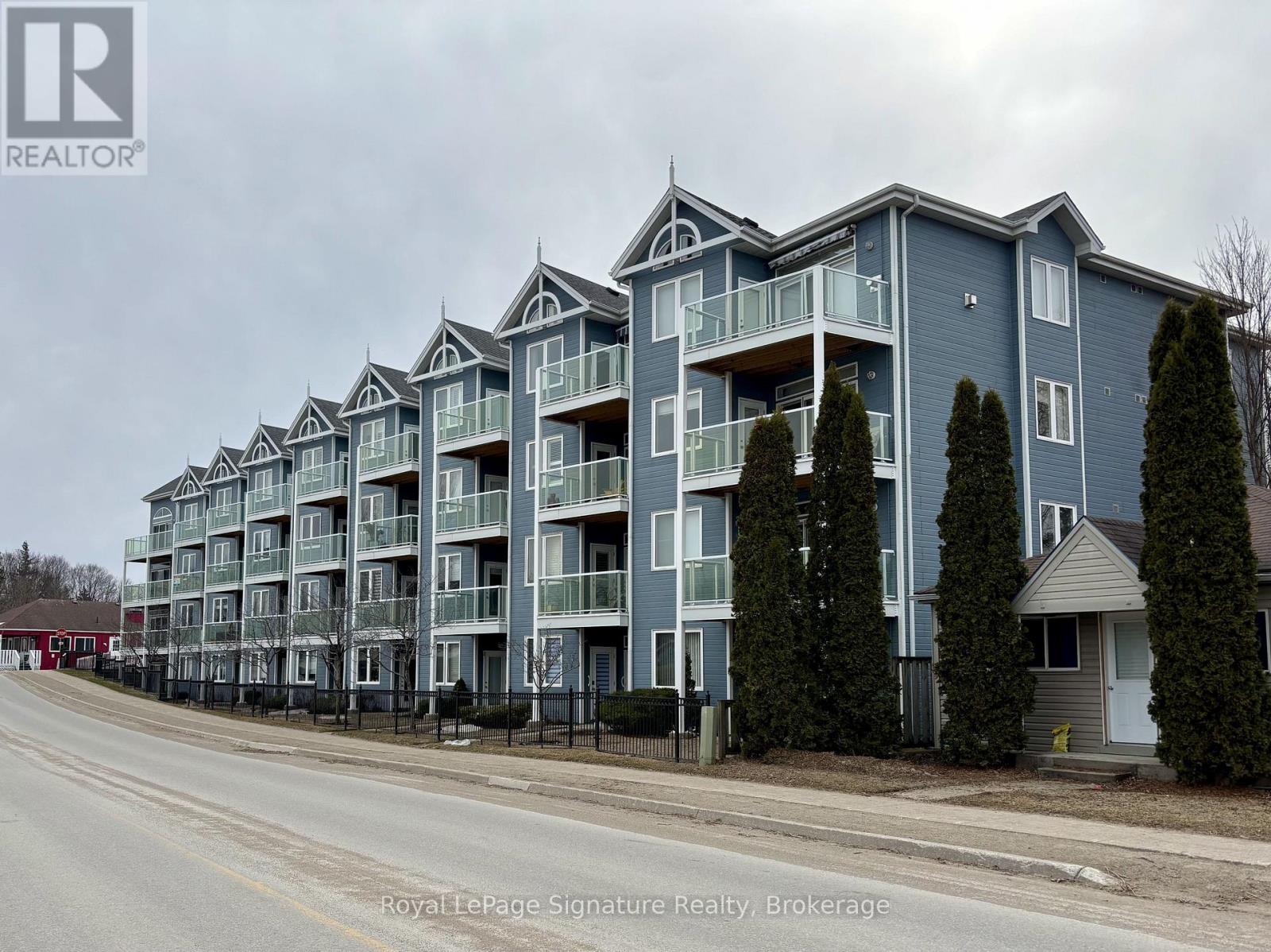 A large apartment complex with multiple balconies and trees in front.