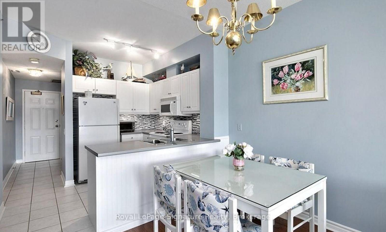 A kitchen with a table and chairs in front of a fridge.