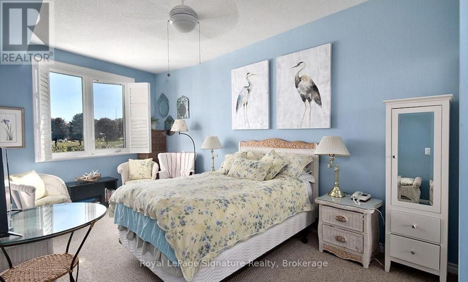 A bedroom with a bed, nightstand, and chair.