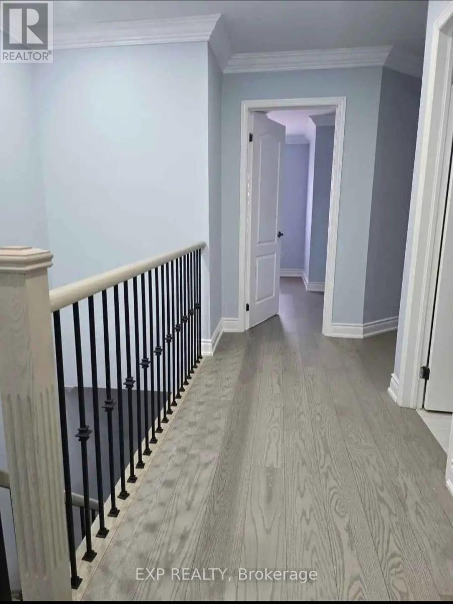 A hallway with a wooden floor and a black railing.